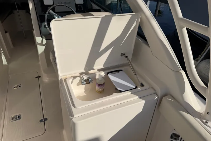 Slide: The Image of 2013 Pursuit DC 265 Dual Console boat sink area with faucet and cutting board. - 10