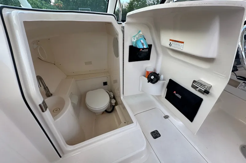 Slide: The Image of 2013 Pursuit DC 265 Dual Console boat interior with compact bathroom amenities. - 17