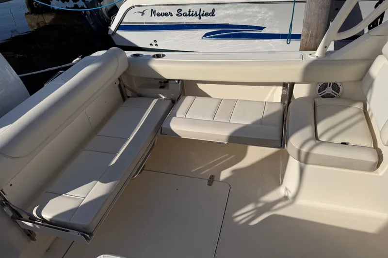 Slide: The Image of 2013 Pursuit DC 265 Dual Console boat interior with white seating and "Never Satisfied" name visible. - 13