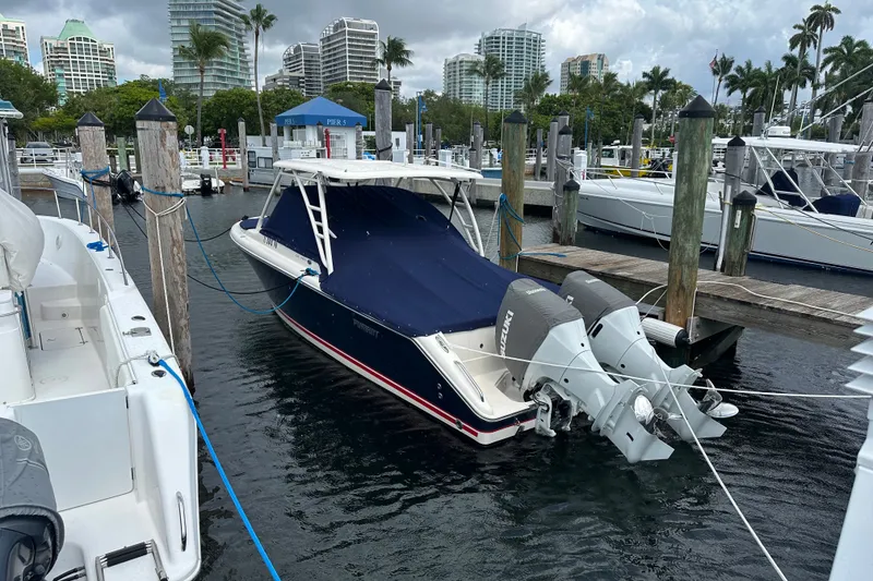 Slide: The Image of 2013 Pursuit DC 265 Dual Console boat docked at marina with city skyline. - 4