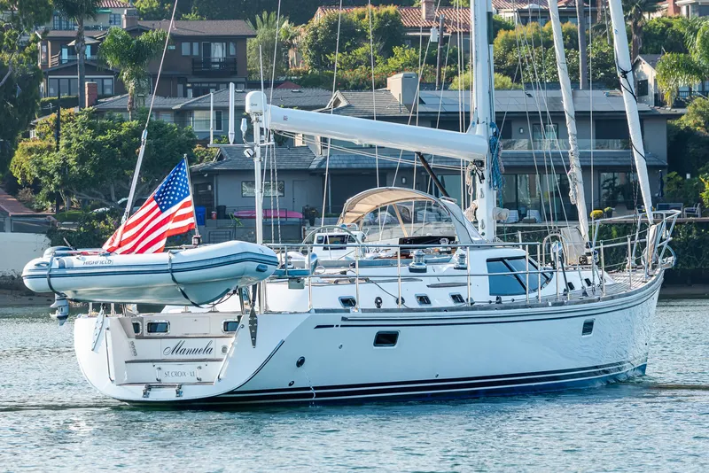 The Image of Sailing yacht Hylas 56, 2011 model, with American flag, docked near waterfront homes. - 0
