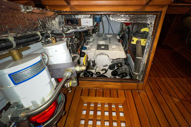 Slide: The Image of Engine room of a 2011 Hylas 56 yacht, showcasing mechanical components and wooden flooring. - 19