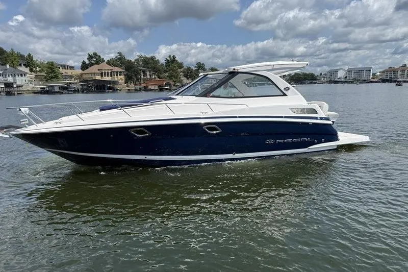 Slide: The Image of 2019 Regal 35 Sport Coupe boat cruising on a scenic lake under a cloudy sky. - 4