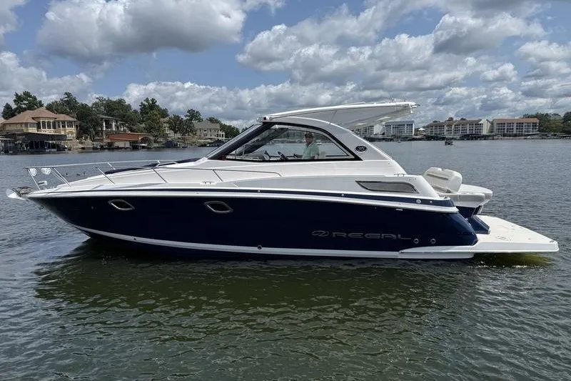 Slide: The Image of 2019 Regal 35 Sport Coupe boat on a lake under a cloudy sky. - 5
