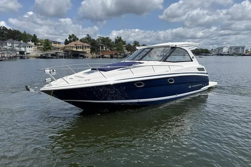 Slide: The Image of 2019 Regal 35 Sport Coupe boat cruising on a scenic lake under a cloudy sky. - 3