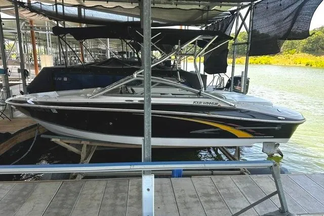 The Image of 2007 Four Winns 200 Horizon boat docked at a marina, featuring sleek black and yellow design. - 0