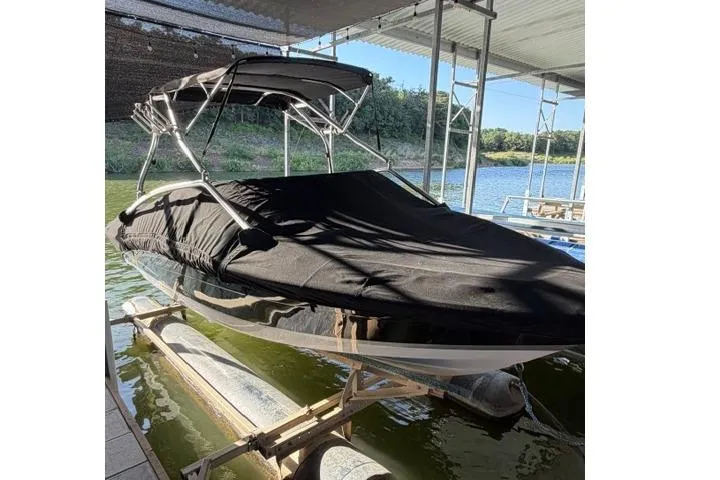 Slide: The Image of 2007 Four Winns 200 Horizon boat with black cover on a lift by the water. - 21