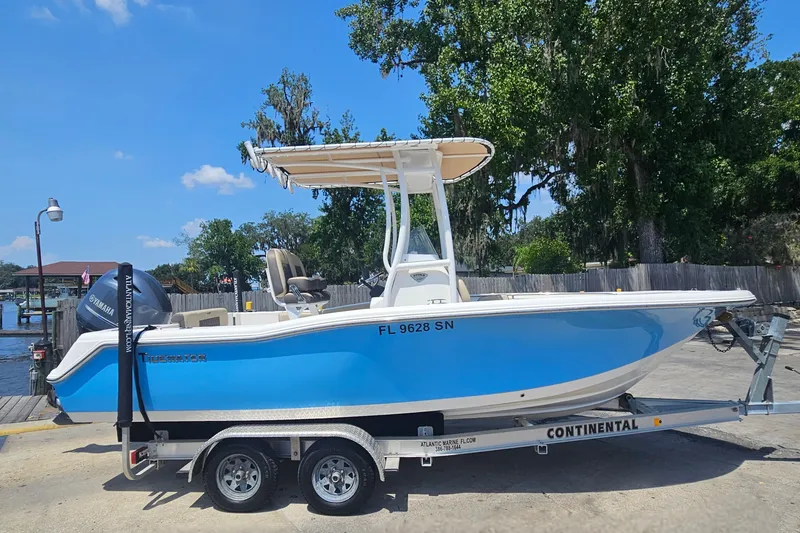 Slide: The Image of 2019 Tidewater 210 LXF boat on trailer, blue hull, Yamaha engine, parked outdoors. - 2