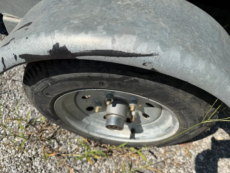 Slide: The Image of Close-up of a boat trailer wheel on gravel. The tire is worn, and the metal is rusty. - 9