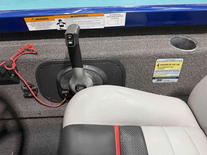 Slide: The Image of Close-up of the control area in a 2017 Triton 18CTX boat, featuring a gear lever and warning labels. - 12