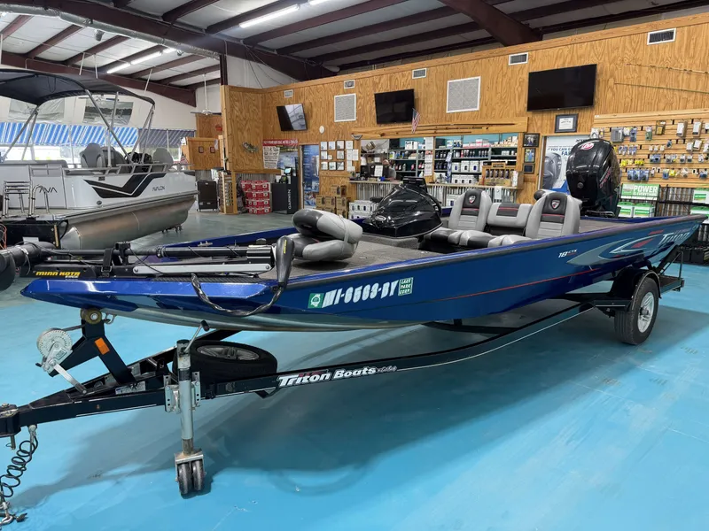 Slide: The Image of A blue 2017 Triton 18CTX in a showroom. It features an outboard motor and gray seats. - 7