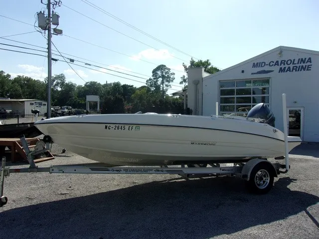 The Image of A white 2017 Stingray 182 SC boat on a trailer in front of a marine shop. - 1