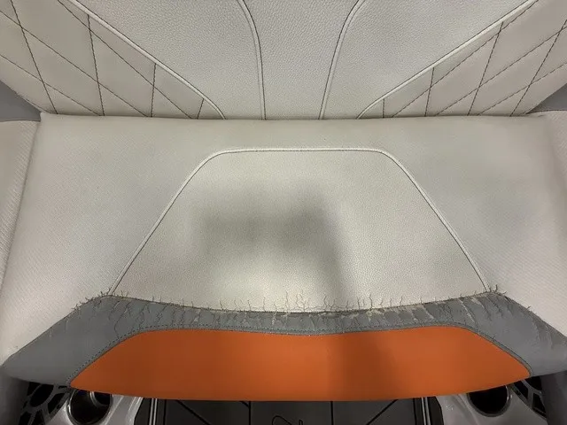 Slide: The Image of Close-up of a seat with white and gray upholstery, orange accent, and visible stitching. - 24