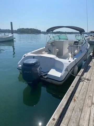 Slide: The Image of A white boat docked with an outboard motor and a black sunshade, floating on calm water. - 2