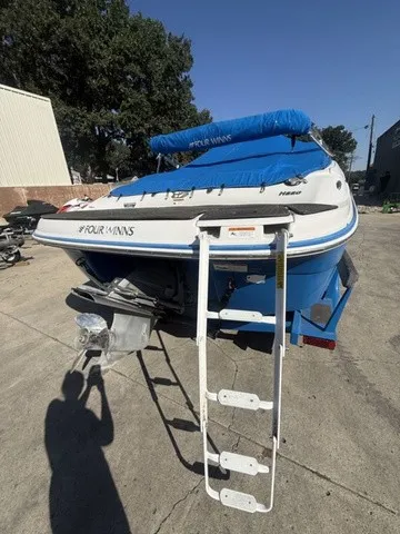 Slide: The Image of A 2008 Four Winns H220 boat with a blue cover and ladder at the stern. - 19
