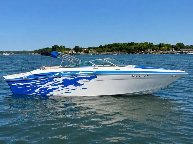 The Image of A 2008 Four Winns H220 boat with blue and white paint on a calm lake. - 1