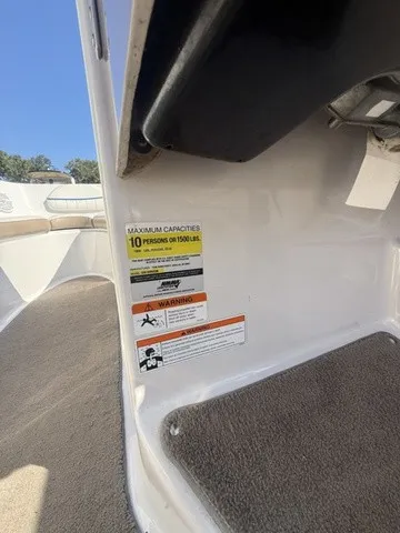 Slide: The Image of Close-up of a boat sticker with capacity and warning information. Carpeted floor and seating area visible. - 24