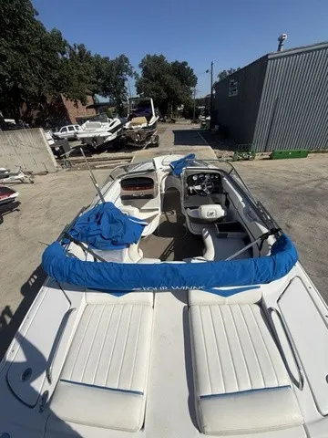 Slide: The Image of A 2008 Four Winns H220 boat with open deck and blue covers, parked in a yard. - 18