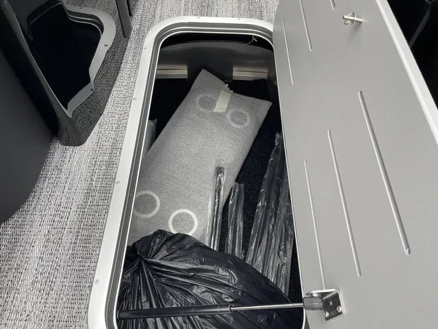 Slide: The Image of An open storage compartment on a boat reveals cushions and packaged items on a gray carpeted floor. - 37