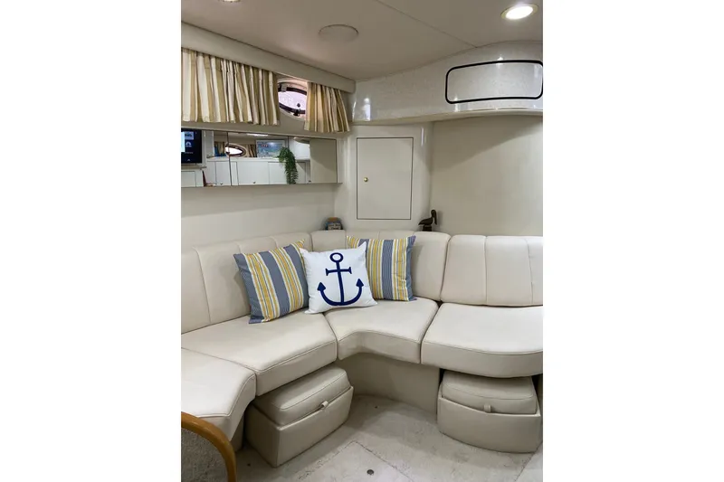 Slide: The Image of Interior of 1997 Sea Ray 450 Sundancer with white seating and nautical-themed pillows. - 29