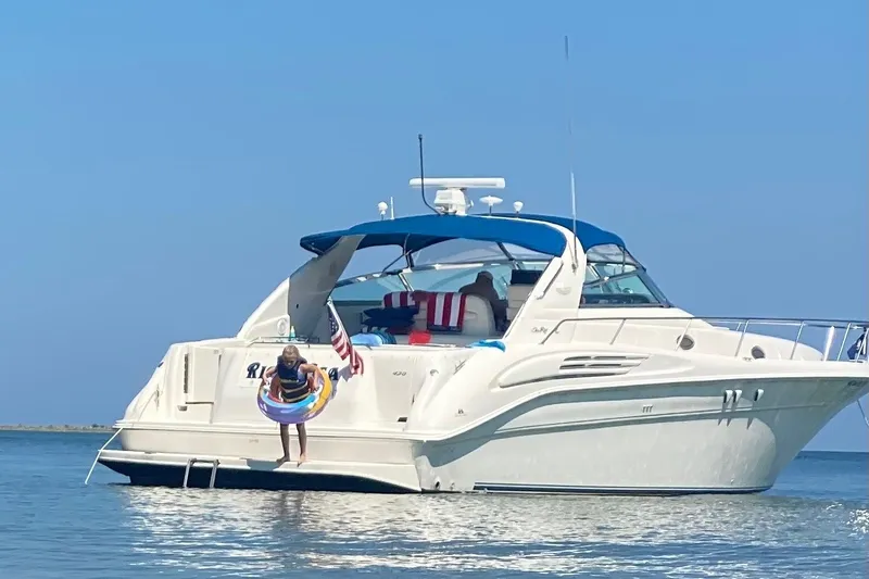 Slide: The Image of A 1997 Sea Ray 450 Sundancer on the water. A person jumps in with a swim ring. - 3