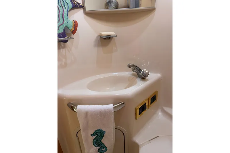 Slide: The Image of Bathroom sink area in a 1997 Sea Ray 450 Sundancer yacht, featuring a seahorse towel. - 42
