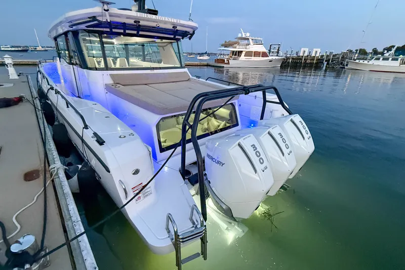 Slide: The Image of 2024 Axopar 45 XC Cross Cabin with triple Mercury engines docked at sunset. - 4