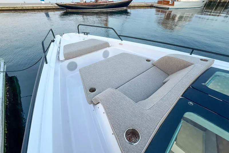 Slide: The Image of 2024 Axopar 45 XC Cross Cabin with cushioned seating on deck by the water. - 13