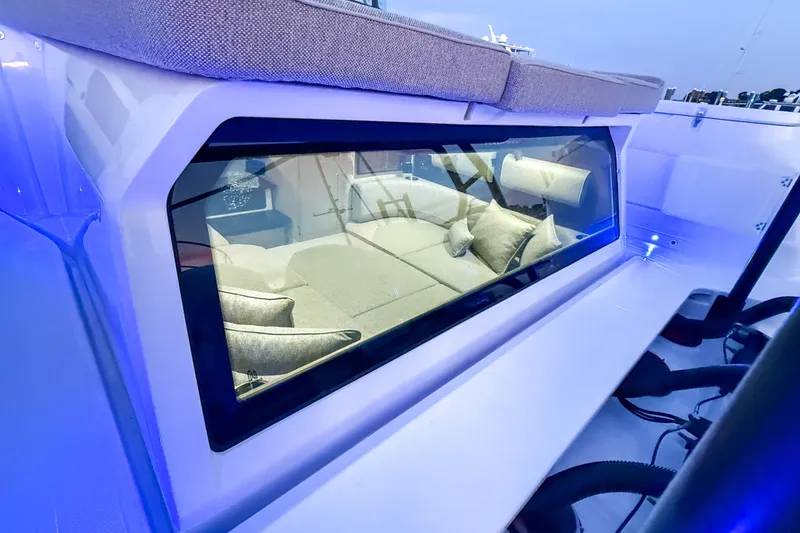 Slide: The Image of 2024 Axopar 45 XC Cross Cabin interior view through window, showcasing seating area. - 7