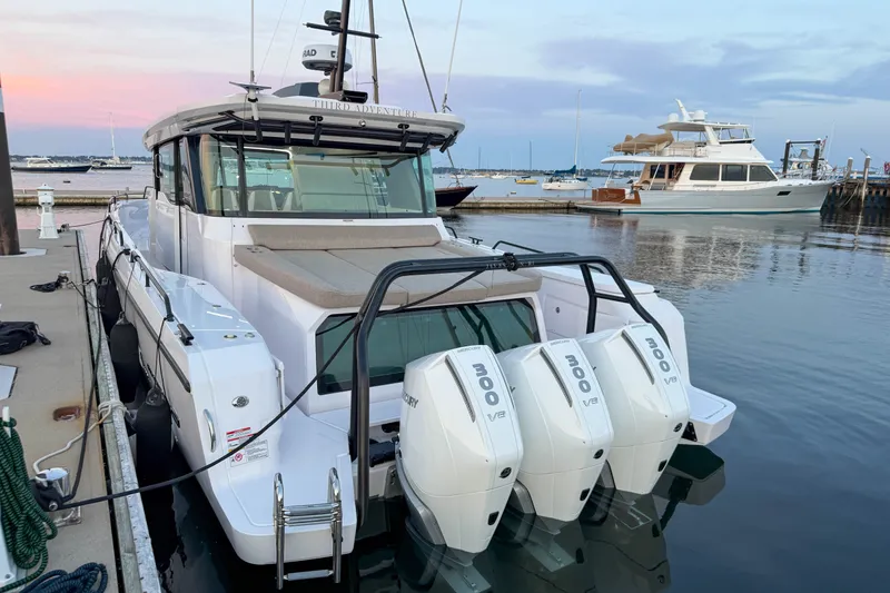 Slide: The Image of 2024 Axopar 45 XC Cross Cabin boat docked with triple outboard engines. - 3