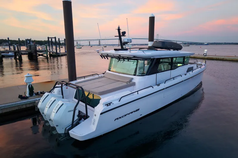 Slide: The Image of 2024 Axopar 45 XC Cross Cabin docked at sunset, showcasing sleek design and powerful engines. - 2