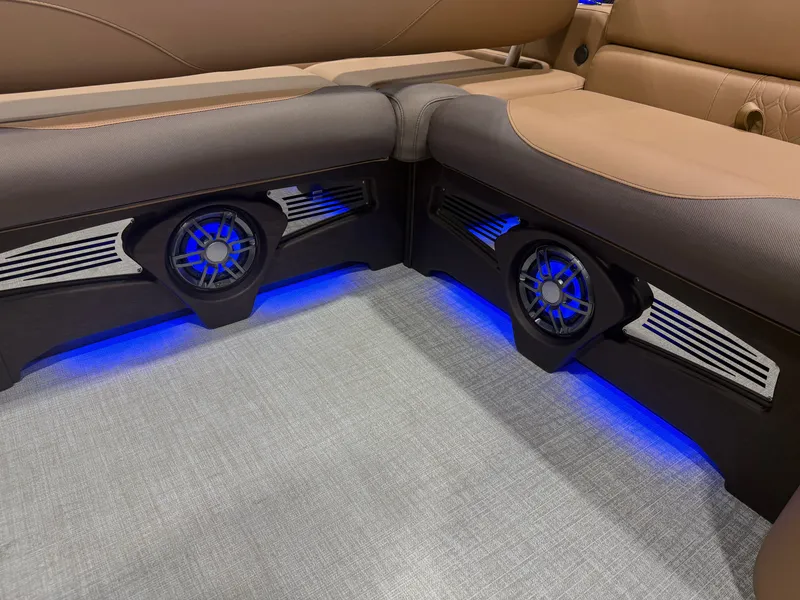Slide: The Image of The interior of the Tahoe LTZ 300HP VRB 2385 Swingback Tritoon features stylish speakers with blue lighting. - 26