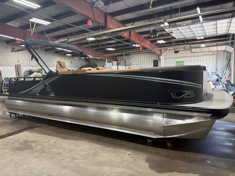Slide: The Image of A modern tritoon with a black hull and beige interior in a warehouse setting. - 50