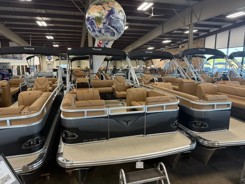 Slide: The Image of Several luxury pontoon boats with beige seating are displayed in a showroom. - 3