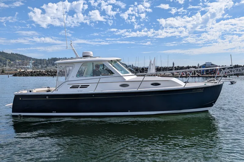Slide: The Image of 2008 Back Cove 29 boat on water, clear sky, marina background. - 1