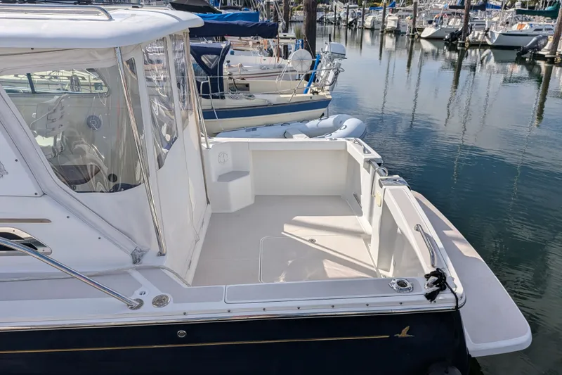 Slide: The Image of 2008 Back Cove 29 boat docked in a marina, showcasing spacious deck and sleek design. - 11