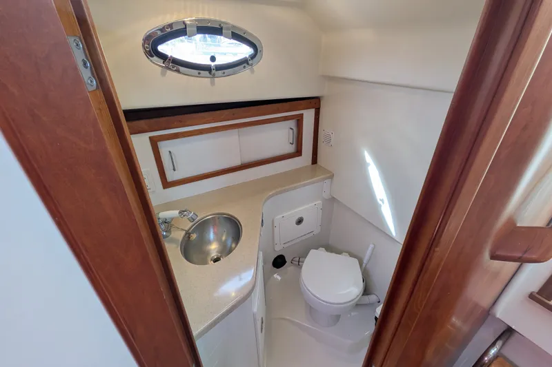 Slide: The Image of 2008 Back Cove 29 yacht bathroom with sink, toilet, and storage cabinets. - 34