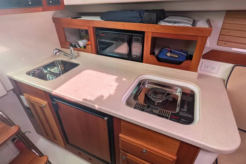 Slide: The Image of 2008 Back Cove 29 yacht galley with sink, stove, microwave, and storage cabinets. - 28