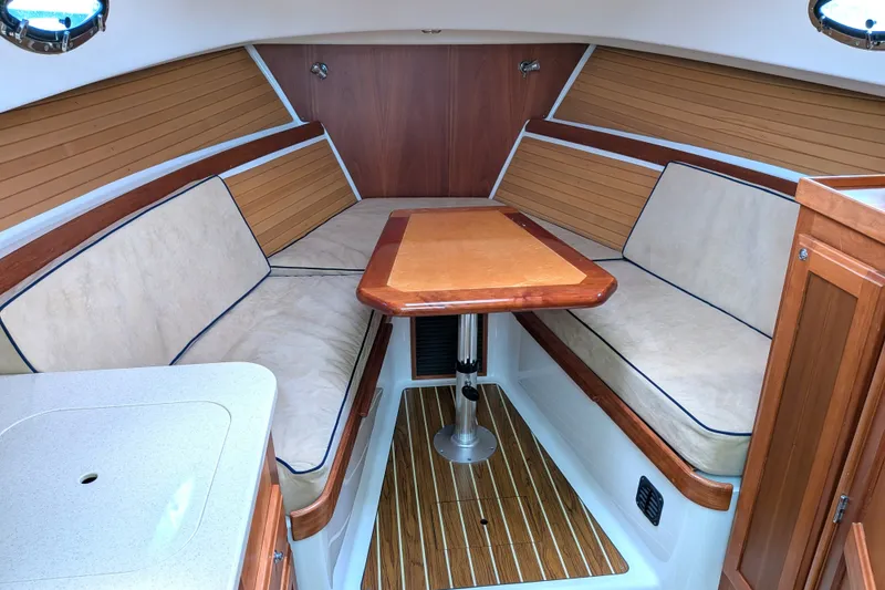 Slide: The Image of 2008 Back Cove 29 boat interior with cushioned seating and wooden table. - 25