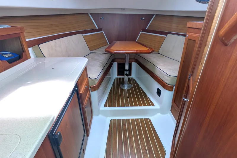 Slide: The Image of 2008 Back Cove 29 interior with wood accents, cushioned seating, and compact kitchenette. - 26