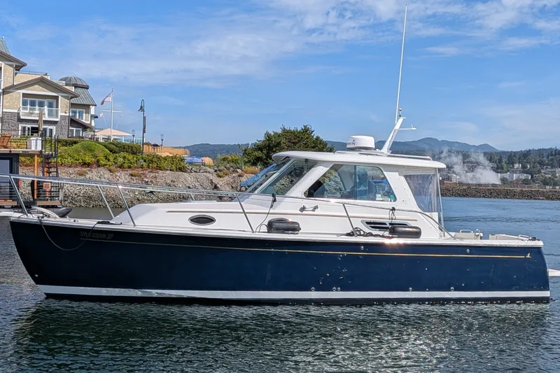 The Image of 2008 Back Cove 29 boat docked near waterfront homes, under clear blue skies. - 0