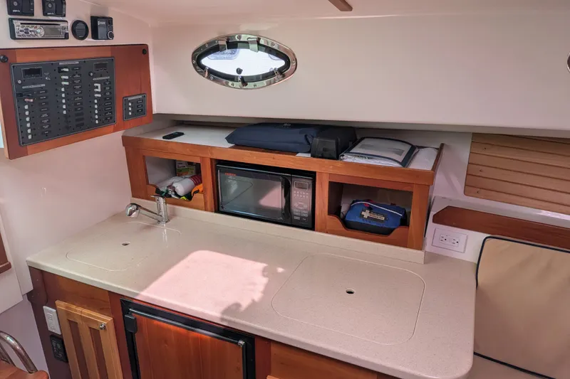 Slide: The Image of Interior of a 2008 Back Cove 29 boat featuring a compact kitchen area with a sink and microwave. - 27