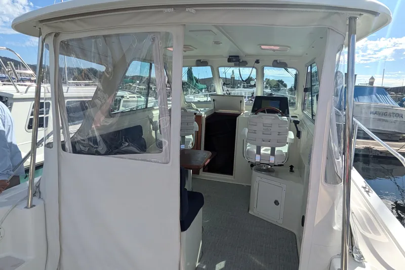 Slide: The Image of 2008 Back Cove 29 boat interior with helm, seating, and marina view. - 13