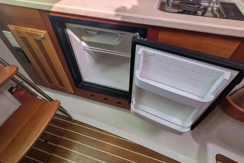 Slide: The Image of 2008 Back Cove 29 boat interior with open mini fridge and compact kitchen area. - 31