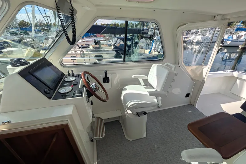 Slide: The Image of 2008 Back Cove 29 boat interior with helm, steering wheel, and marina view. - 20