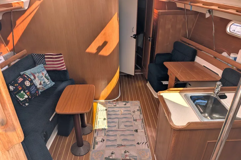 Slide: The Image of Interior of 2003 Catalina 350 sailboat with cozy seating, wooden table, and kitchenette. - 21