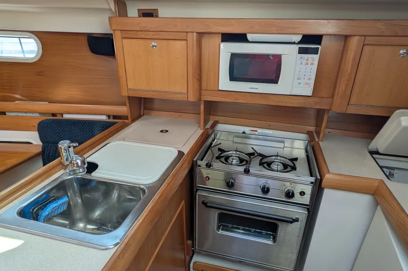 Slide: The Image of 2003 Catalina 350 yacht kitchen with stove, microwave, and sink. - 25