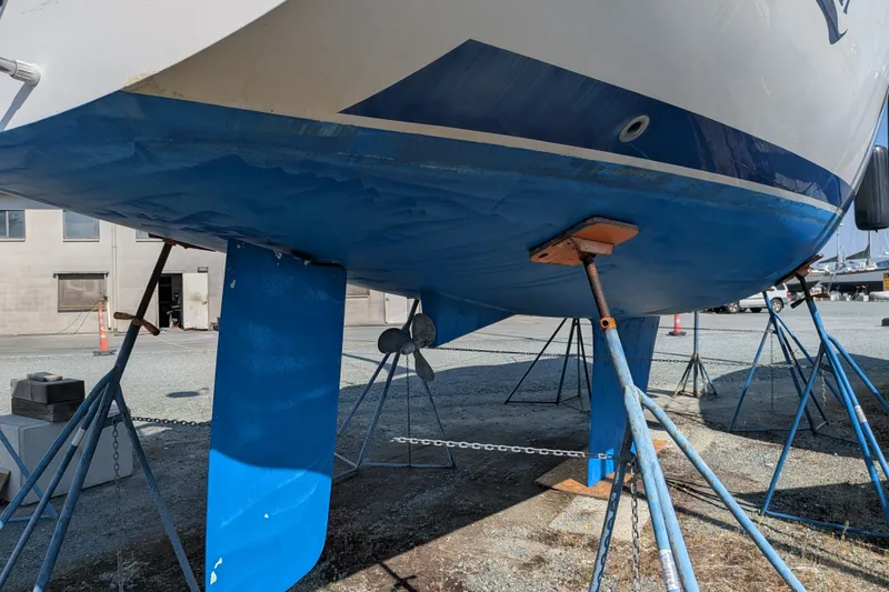 Slide: The Image of 2003 Catalina 350 sailboat on stands, showcasing blue hull and keel in a boatyard. - 41