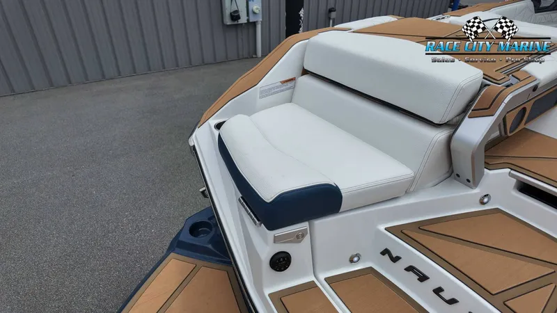 Slide: The Image of The image shows the stern of a Nautique P23 boat with white and blue upholstery. - 13