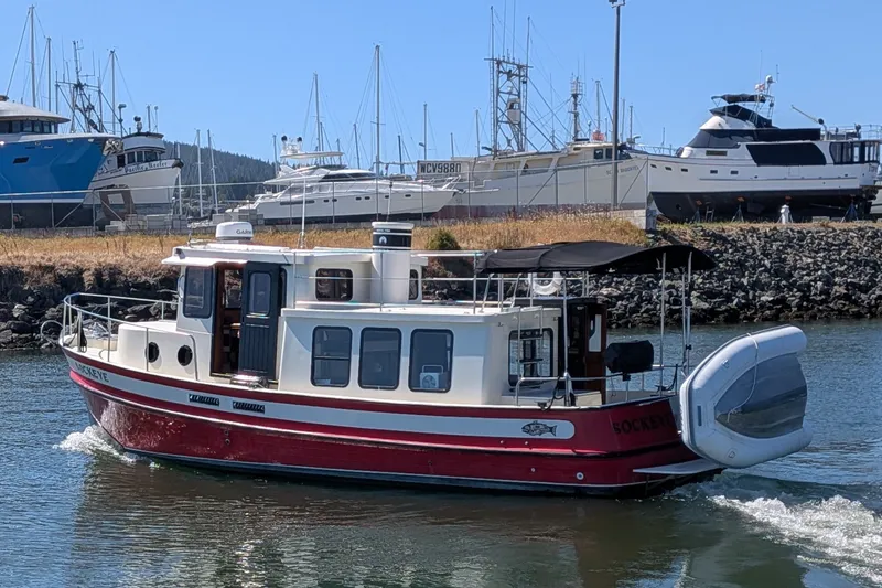 Slide: The Image of 1997 Nordic Tug 32 cruising in a marina with other boats docked nearby. - 2